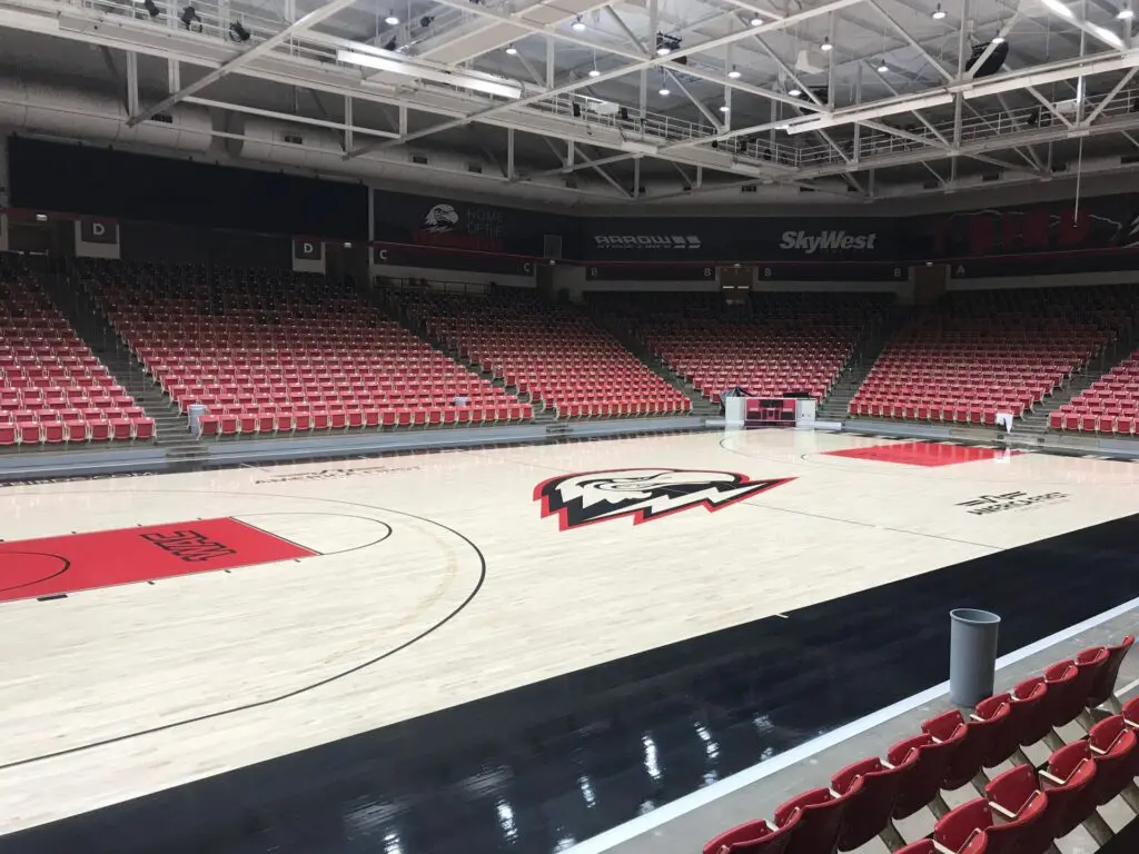 Arena basketball court with a red and black Thunderbird logo at center and red seating on all sides